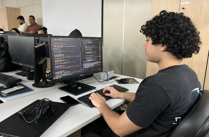 Estagiário sentado diante de computador em estação de trabalho
