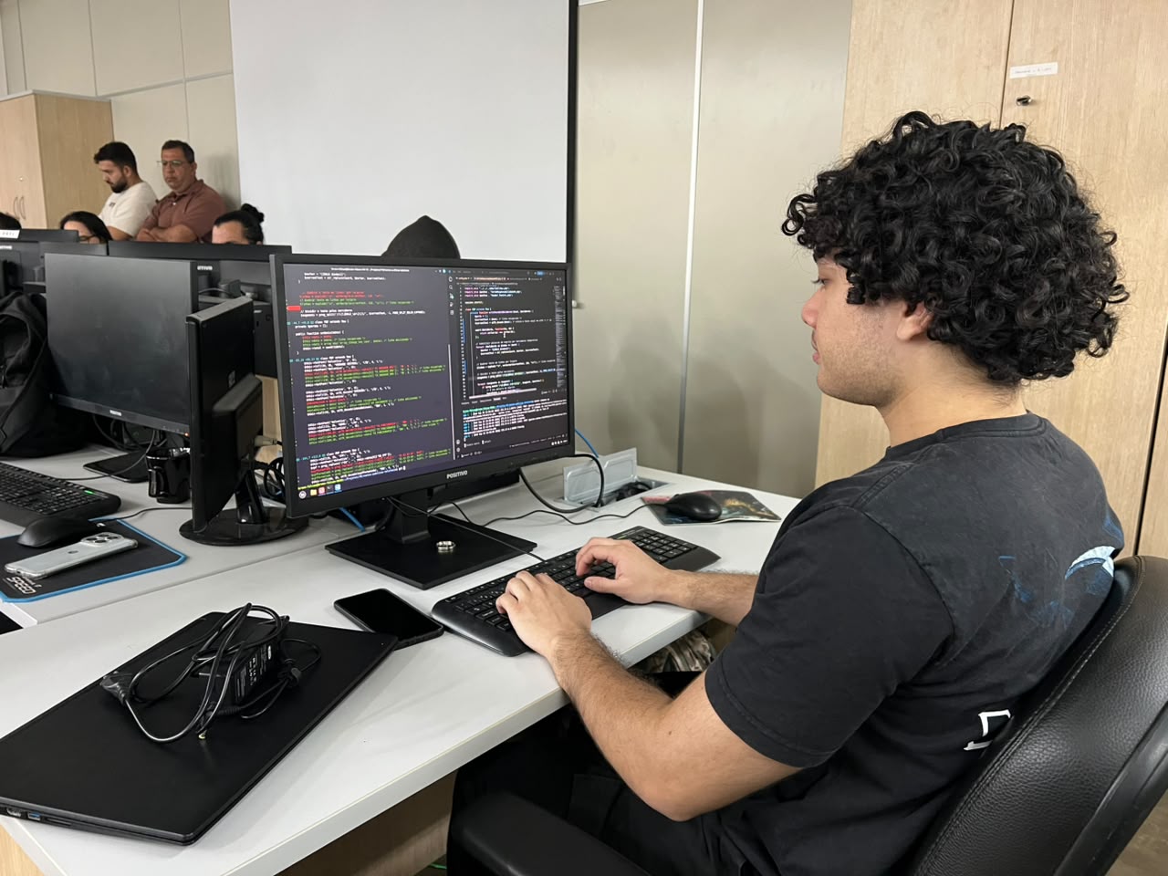 Estagiário sentado diante de computador em estação de trabalho