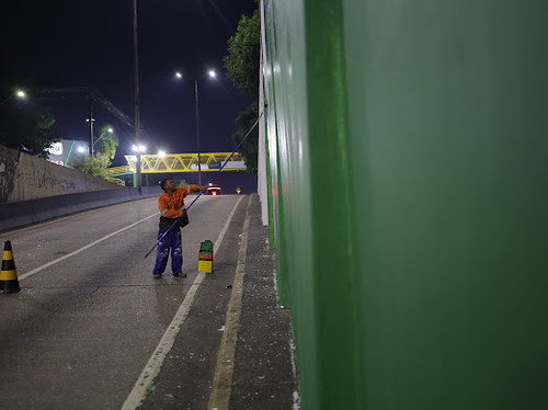 Trabalhador pinta a lateral do viaduto Professora Lilá Borges de Sá à noite